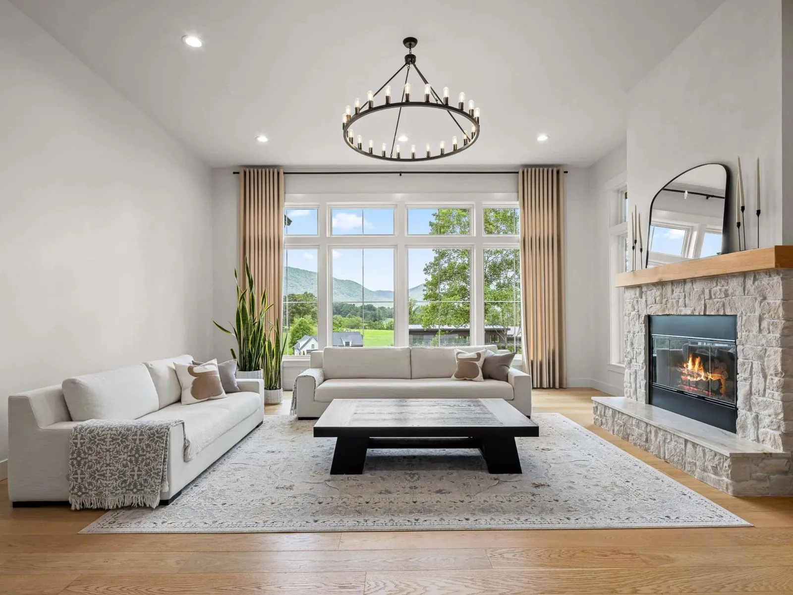 Bright living room with a stone fireplace and mountain views through tall windows, Western North Carolina